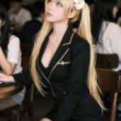 ZIT 01，A blonde woman in a black blazer with gold accents sits at a table.