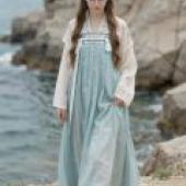 British female students studying in China，A girl is wearing blue dress and standing next to the sea.
