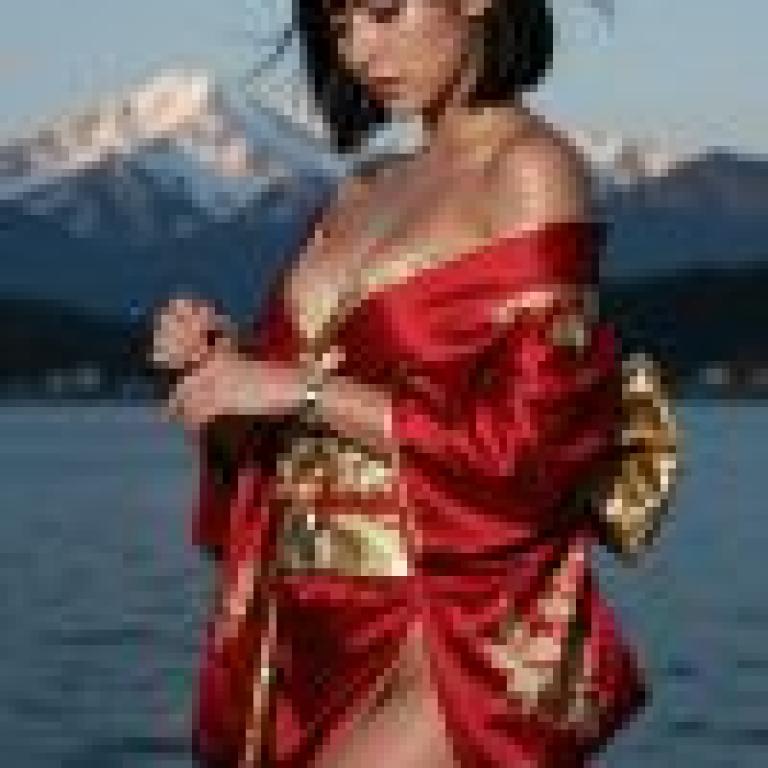 girls，A young girl wearing a red dress standing in front of water and mountains.