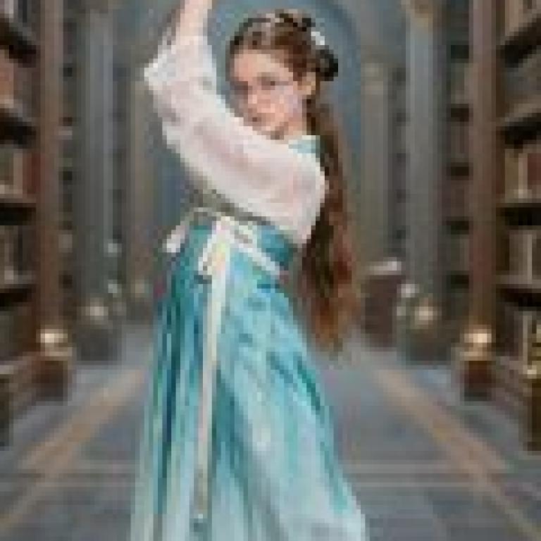 British female students studying in China，Girl in blue dress and white sash holding up her arm.