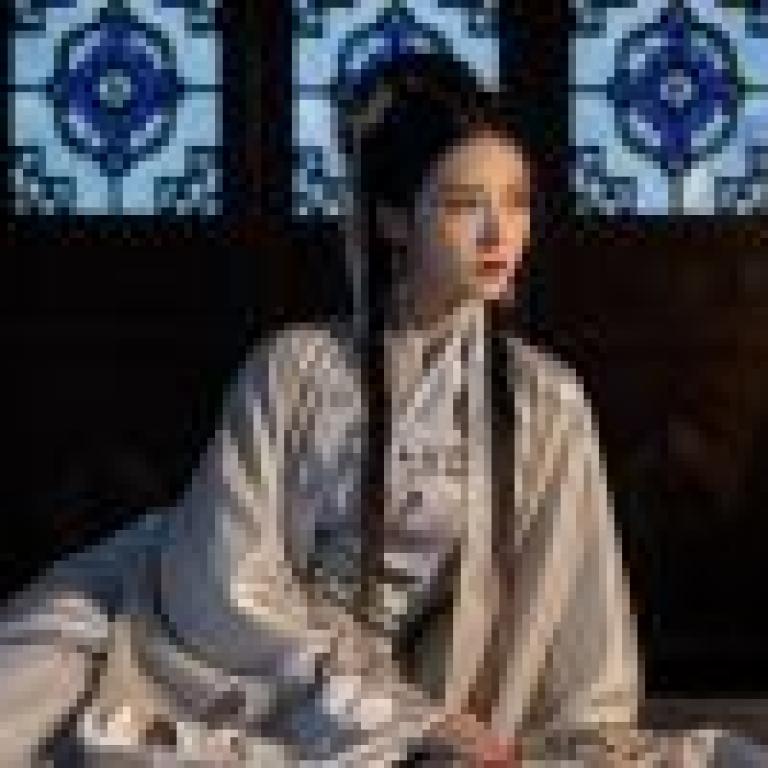 古代女性，一位身穿長裙、頭戴黑色長髮蝴蝶結的女子坐在床上。