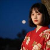 一位身穿紅色和服、上麵點綴著白色花朵的女子正看向她的右邊。