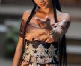 異國風情，一位身著洋裝、佩戴眾多飾品的年輕亞洲女子正在揮手致意。