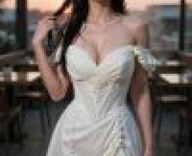 Street beauties，A model wears a white dress in front of tables and chairs.