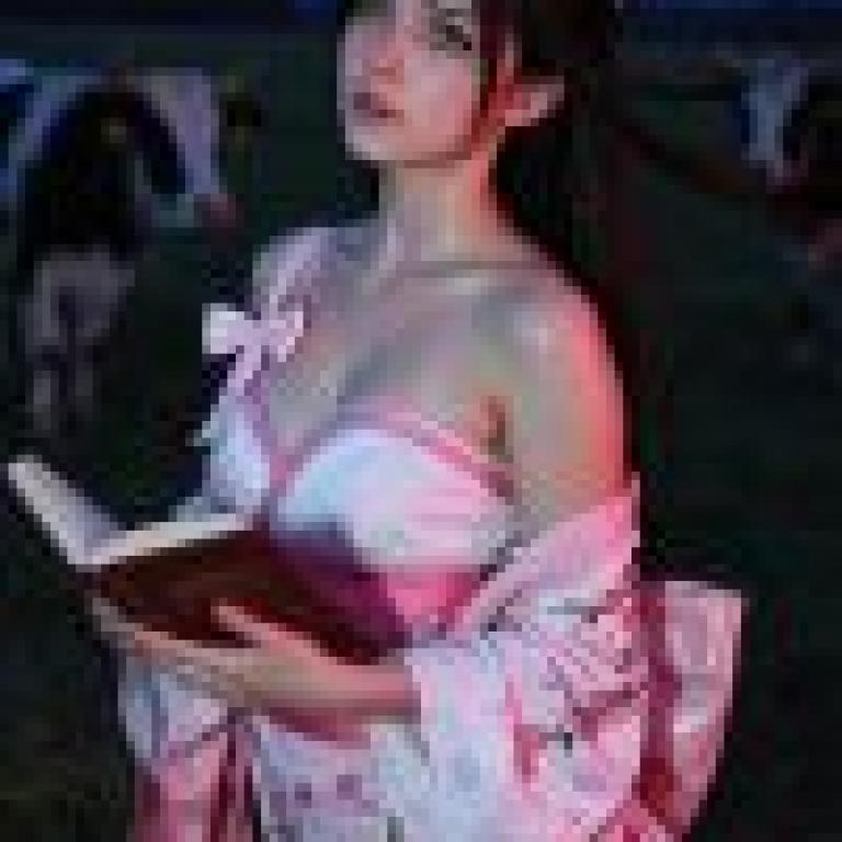故事中的和服，一位穿著粉紅色和服的女子在牛群前拿著一本書。