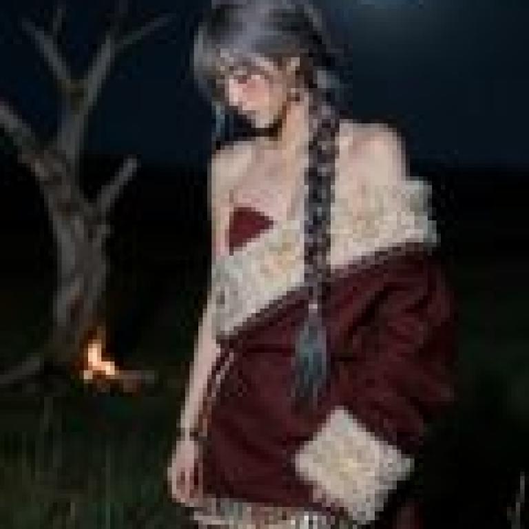 Memories of my trip to Tibet，Woman in red dress stands in front of campfire with her arms crossed.