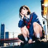 A corner of the city，A girl sitting on a wall with a city in the background.