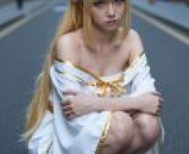 ZIT 01，A woman in white with blonde hair and gold bow sitting on the street.