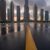 Roads leading to the city，A black asphalt city street with yellow lane markings.