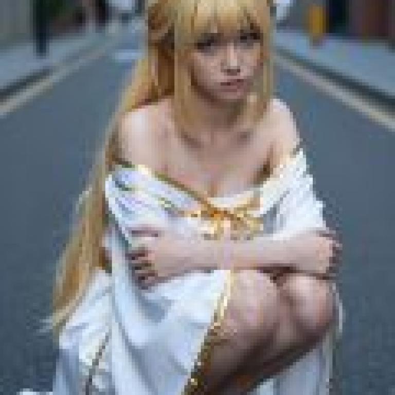ZIT 01，A woman in white with blonde hair and gold bow sitting on the street.