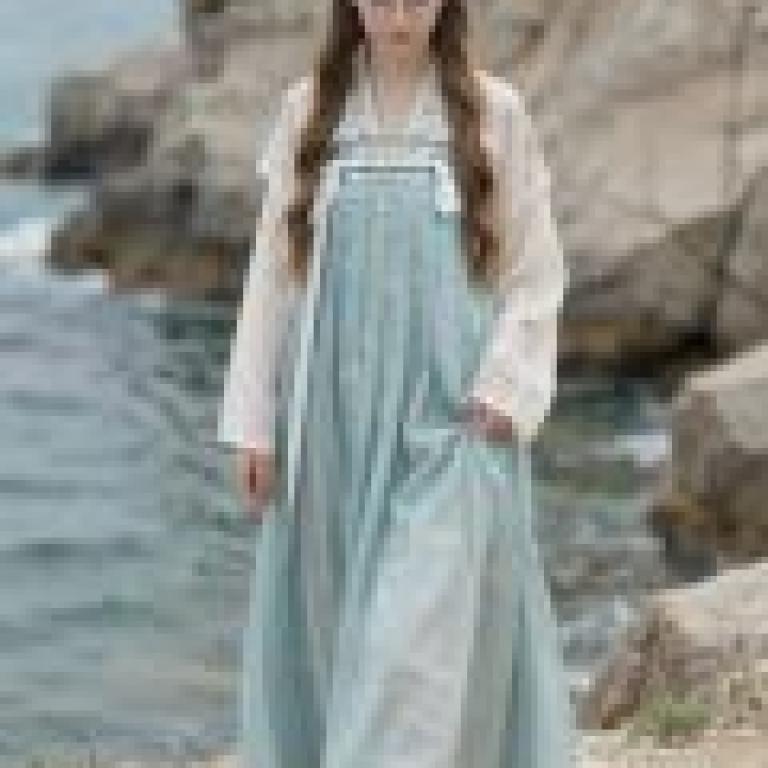 British female students studying in China，A girl is wearing blue dress and standing next to the sea.