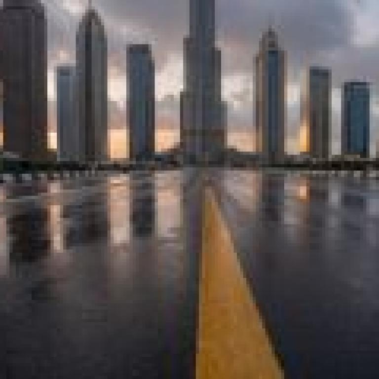 Roads leading to the city，A black asphalt city street with yellow lane markings.