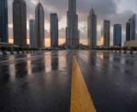 通往市區的道路，一條黑色瀝青路面的城市街道，上面有黃色車道線。